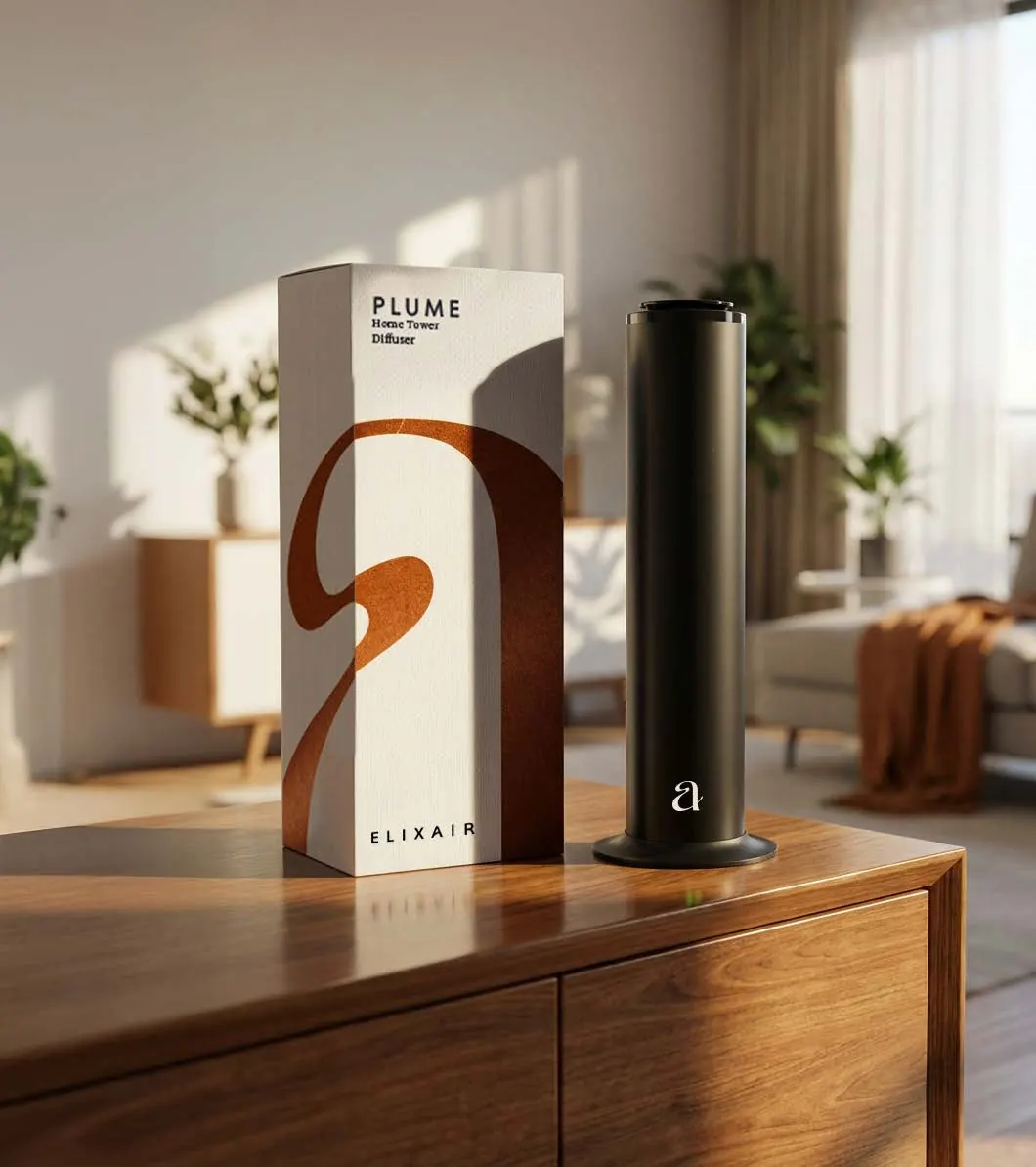PLUME home tower diffuser in matt black beside its white box with a copper monogram, on a walnut sideboard