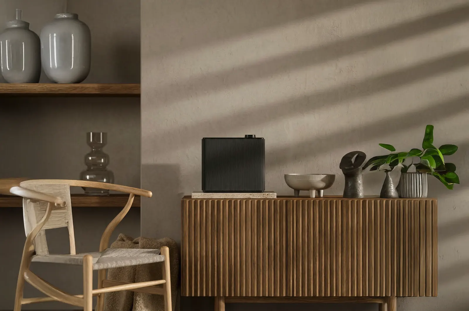 A ribbed black PULSE scent machine on a travertine block, on an oak sideboard in a softly lit room