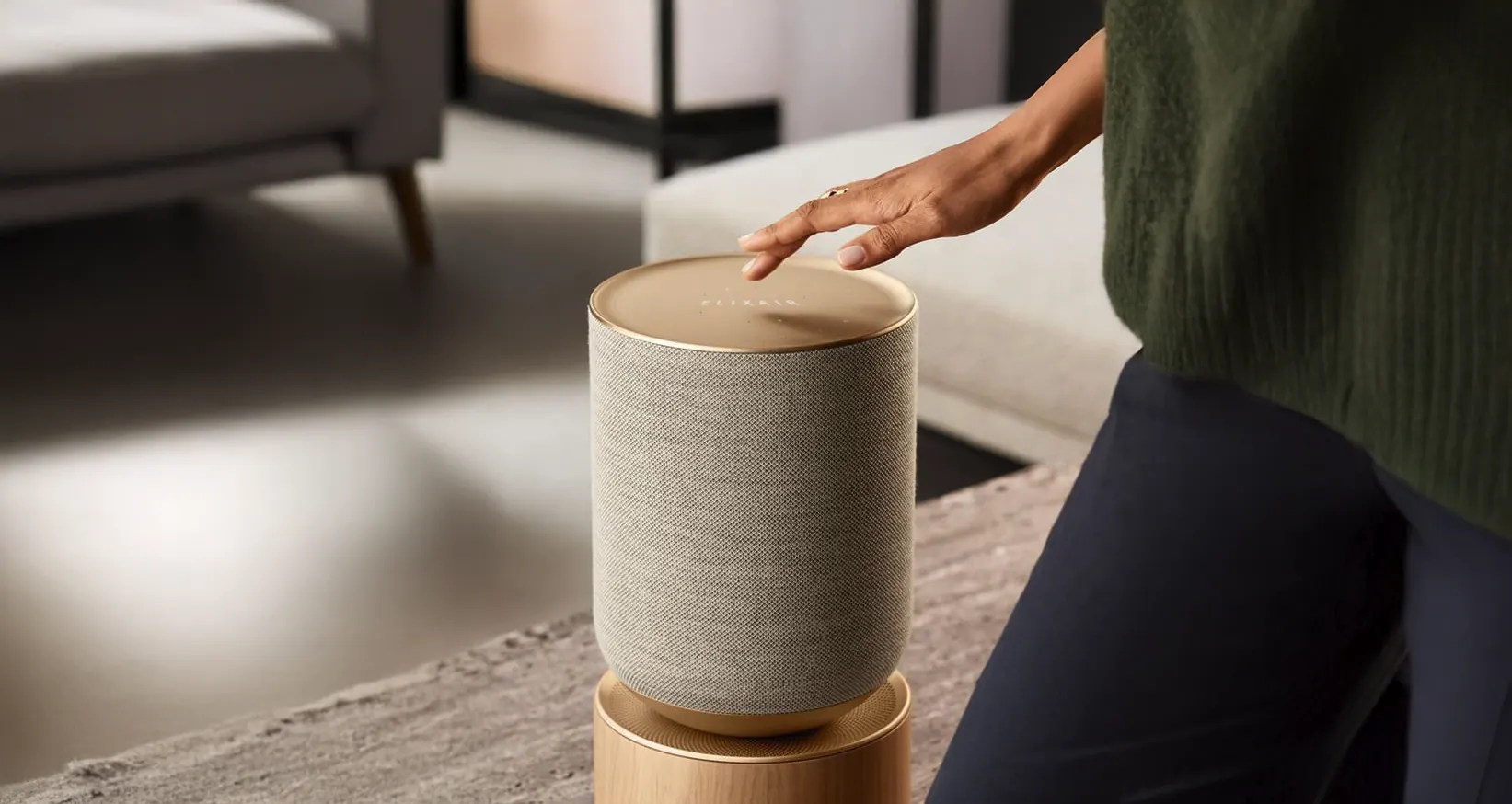 A hand resting on the brass top of a fabric-wrapped Elix Air device